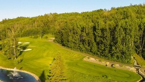 A golf course with a pond, surrounded by dense forest. - 2BR Stylish Suite: Outlets & REC Room|Sep Entrance (Edmonton)