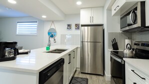 A modern kitchen with white cabinetry, stainless steel appliances, and a built-in dishwasher. - 2BR Stylish Suite: Outlets & REC Room|Sep Entrance (Edmonton)