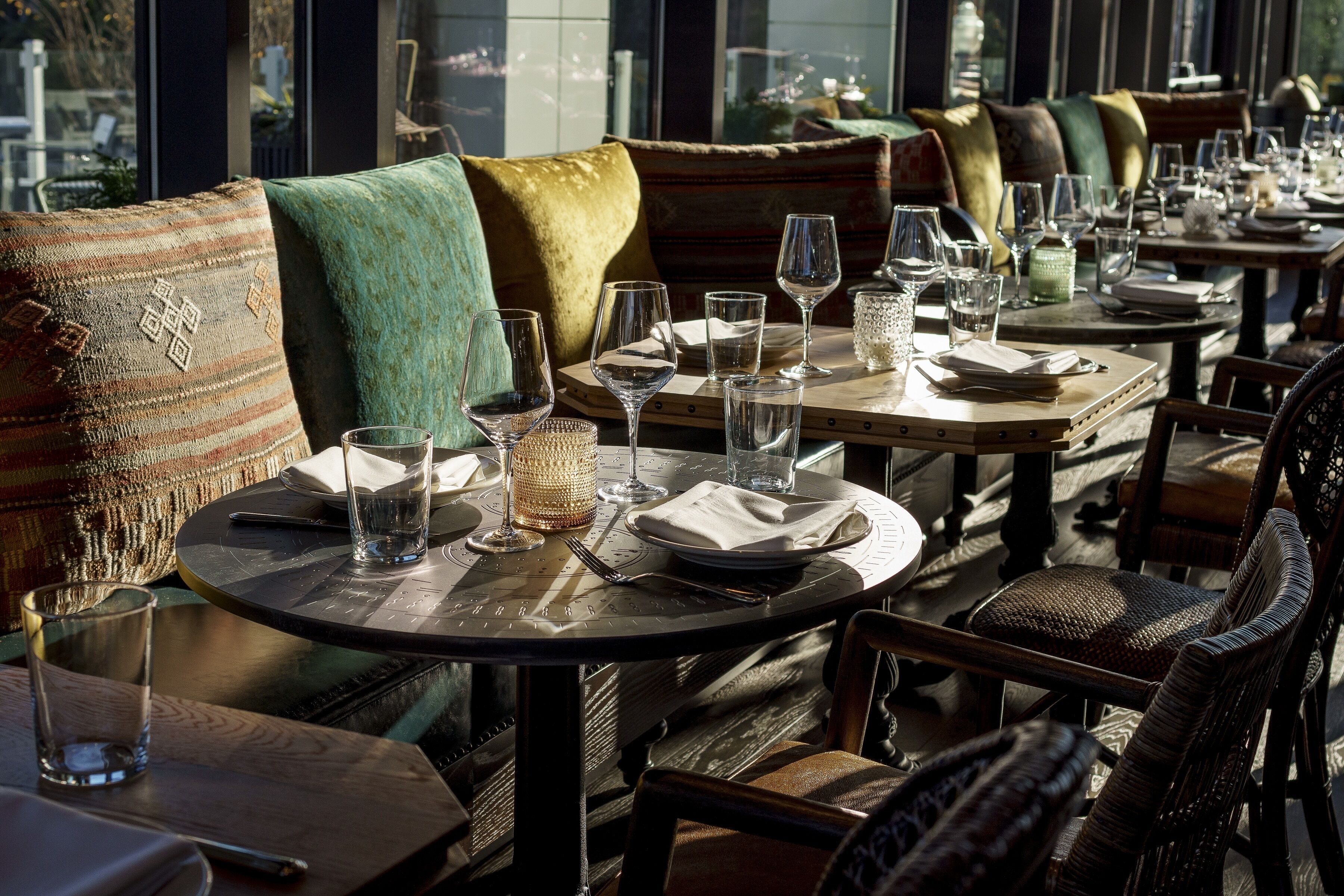 A restaurant with round tables, chairs, and cushioned seating.