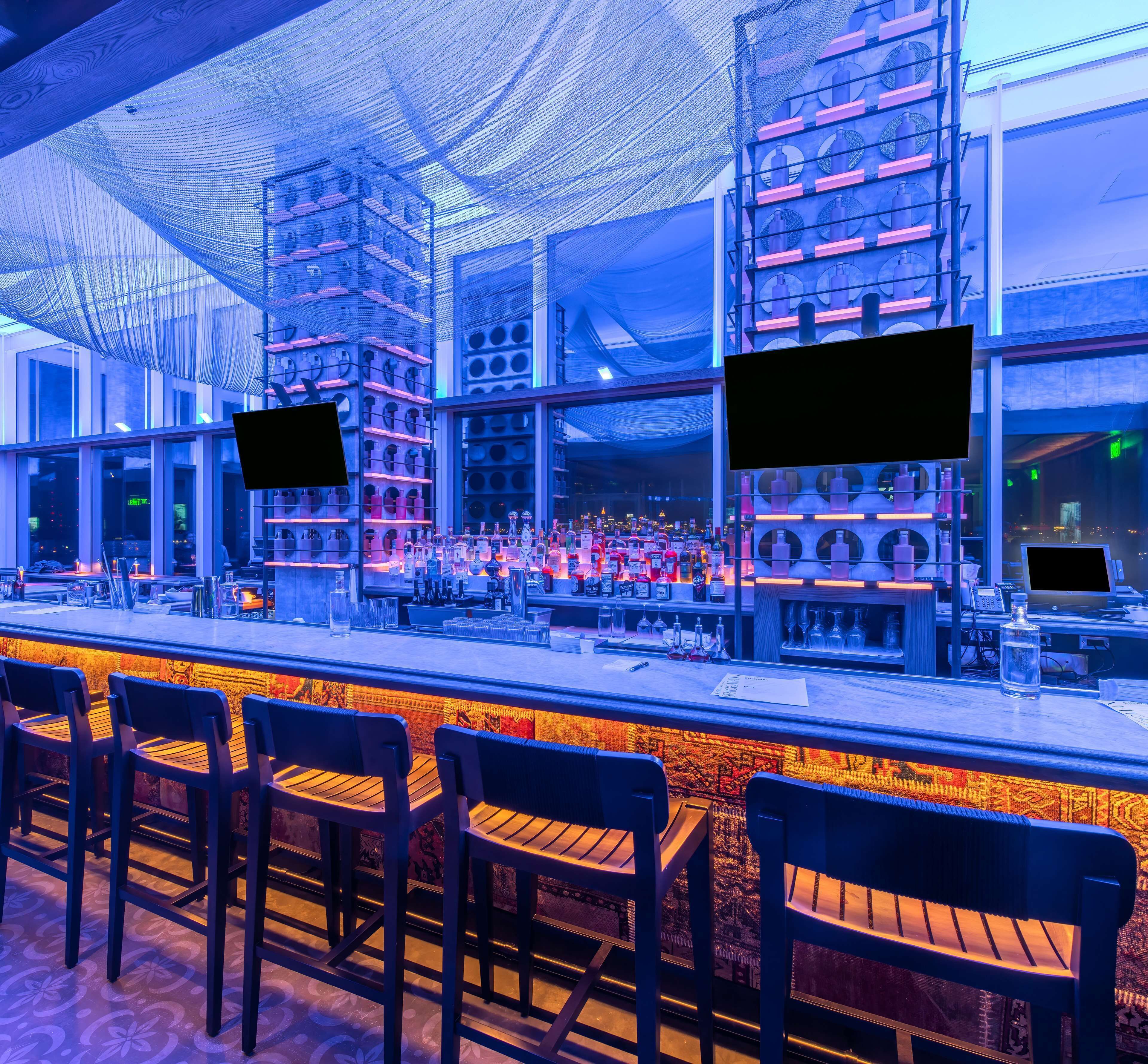 A bar area with multiple seating options, a well-stocked bar counter, and a modern interior design.
