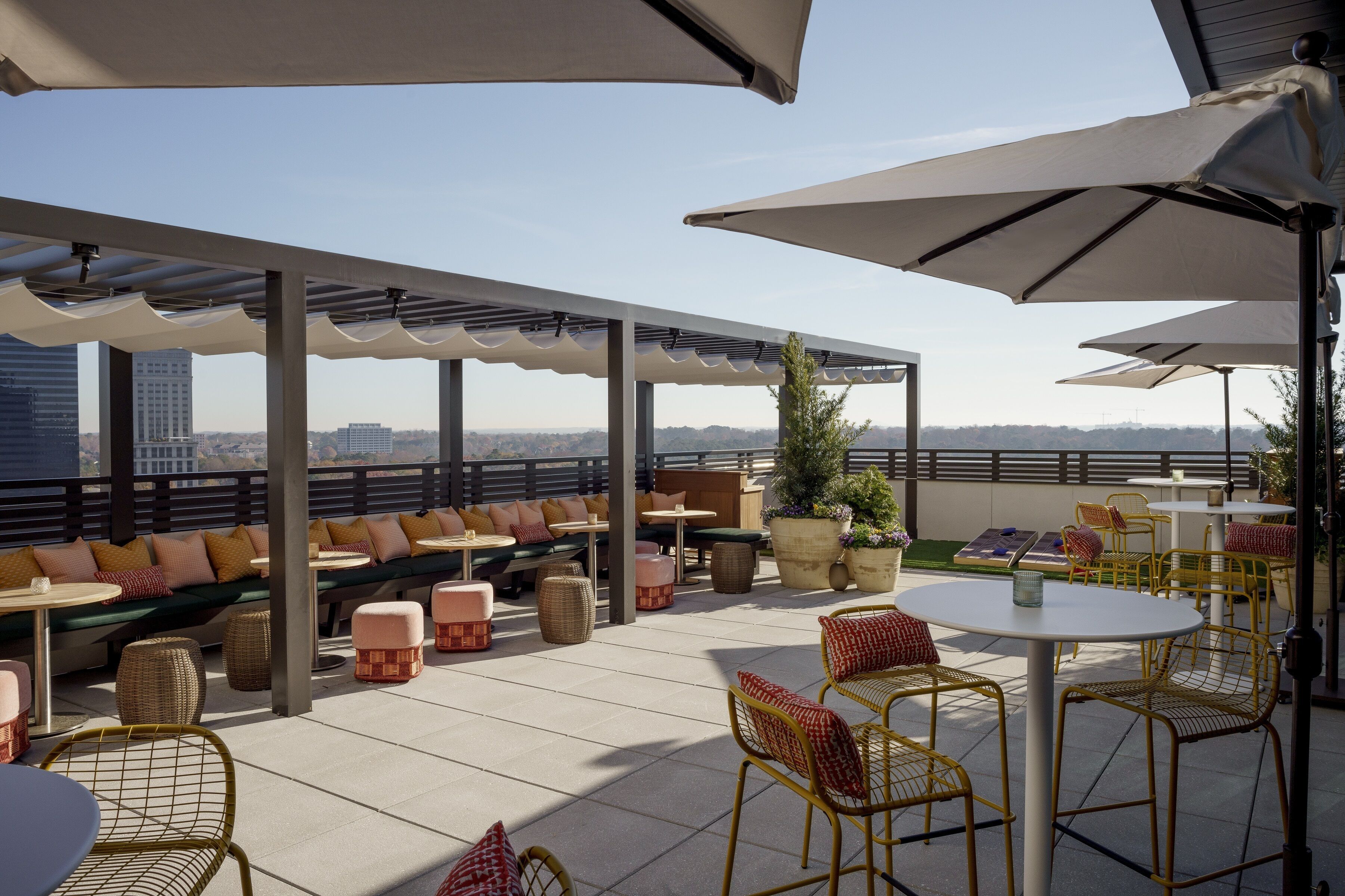 An outdoor seating area with tables and chairs, a covered section with a view of the cityscape.