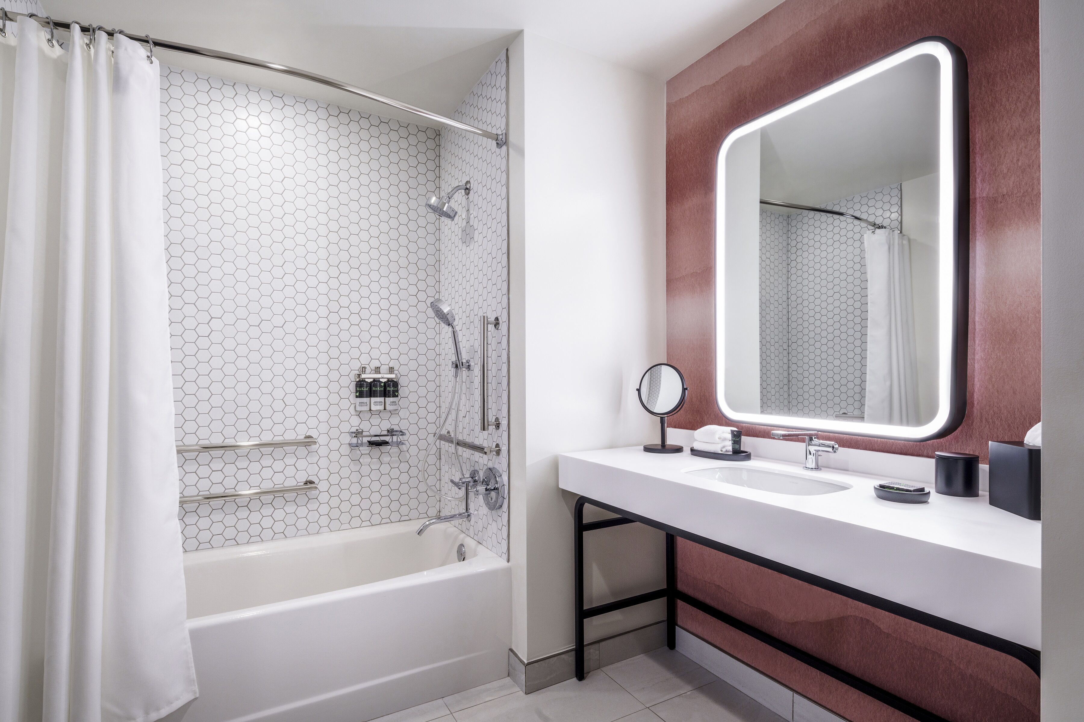 A modern bathroom with a white bathtub, a large mirror, and a vanity with a sink.