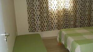 Ein Zimmer mit einem grünen Bett, einer Wand mit Muster und einem Holzboden.