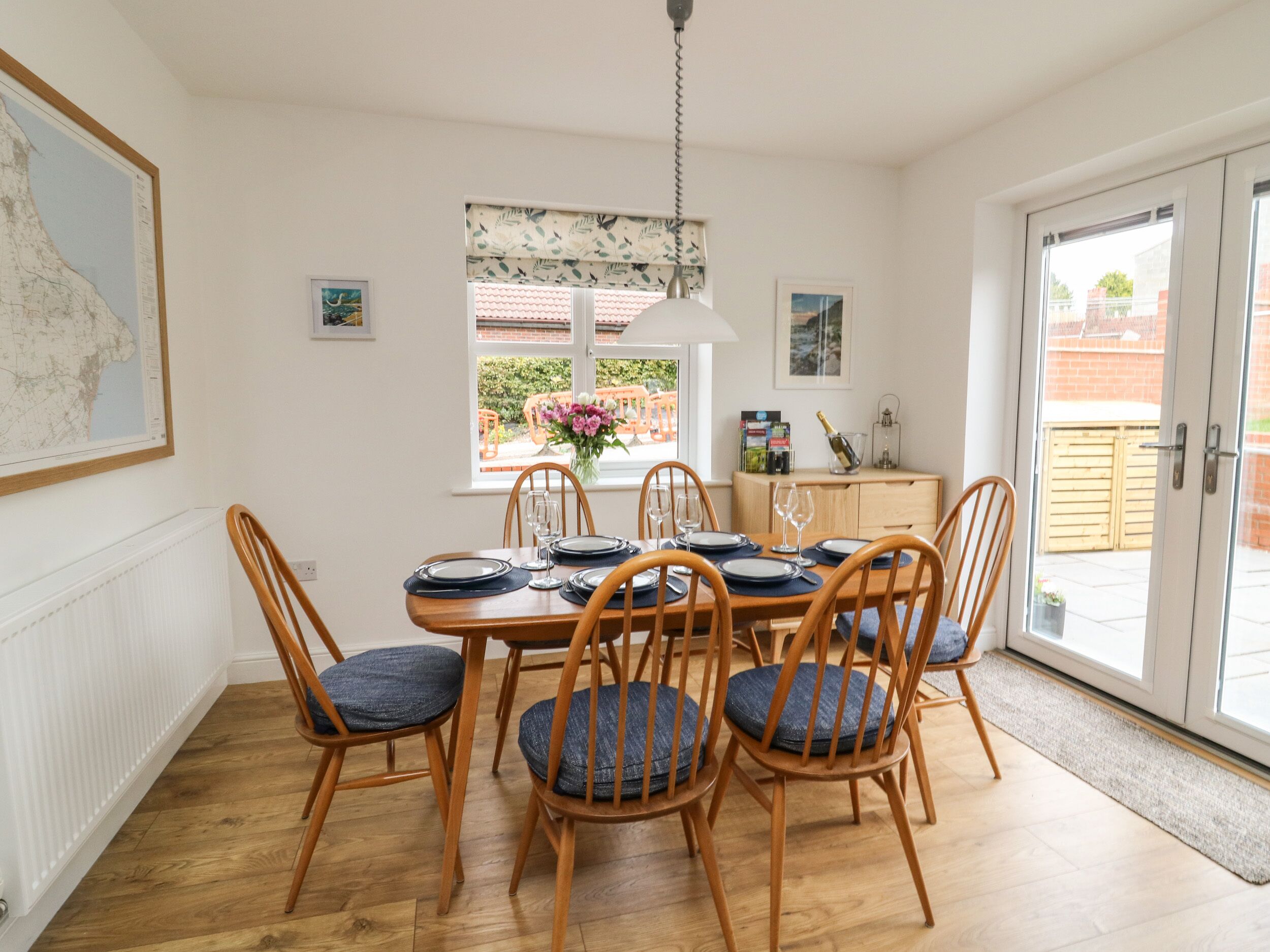 Comedor con mesa de madera dispuesta para seis personas, rodeada por seis sillas de madera con cojines azules.
