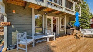 A two-story building with a deck, white outdoor furniture, and a grill. - Mountain Memories in Homewood (Tahoma)