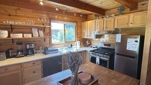 A kitchen with wooden cabinets, a stove, a refrigerator, and a window.