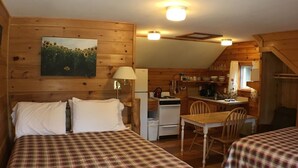 A cabin with two beds, a kitchenette, and a dining area. - Studio Suite 1 with full kitchen  (Stratton)