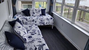 A room with two beds, large windows, and a view of the outdoors.