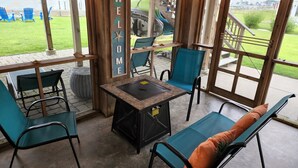 A covered outdoor seating area with a welcome sign, chairs, and a table.