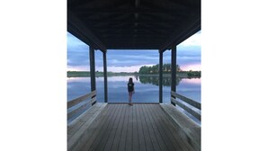 Une jetée en bois s’étendant au-dessus d’une étendue d’eau calme, avec une personne debout à son extrémité.