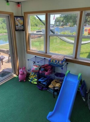 A room with a window, a slide, and storage bins filled with bags.