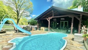 A swimming pool with a unique shape, a slide, and a covered pavilion. - Private Adirondack Getaway. Close to hiking trails, fishing, public beach. (Clemons)