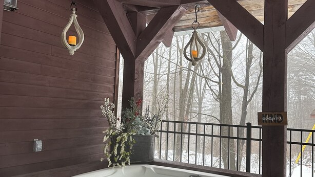 A wooden cabin with a hot tub, hanging lanterns, and a view of snow-covered trees. - Private Adirondack Getaway. Close to hiking trails, fishing, public beach. (Clemons)