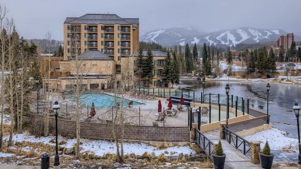 Un hôtel doté d’une piscine, entouré d’un paysage enneigé et avec des montagnes en toile de fond.