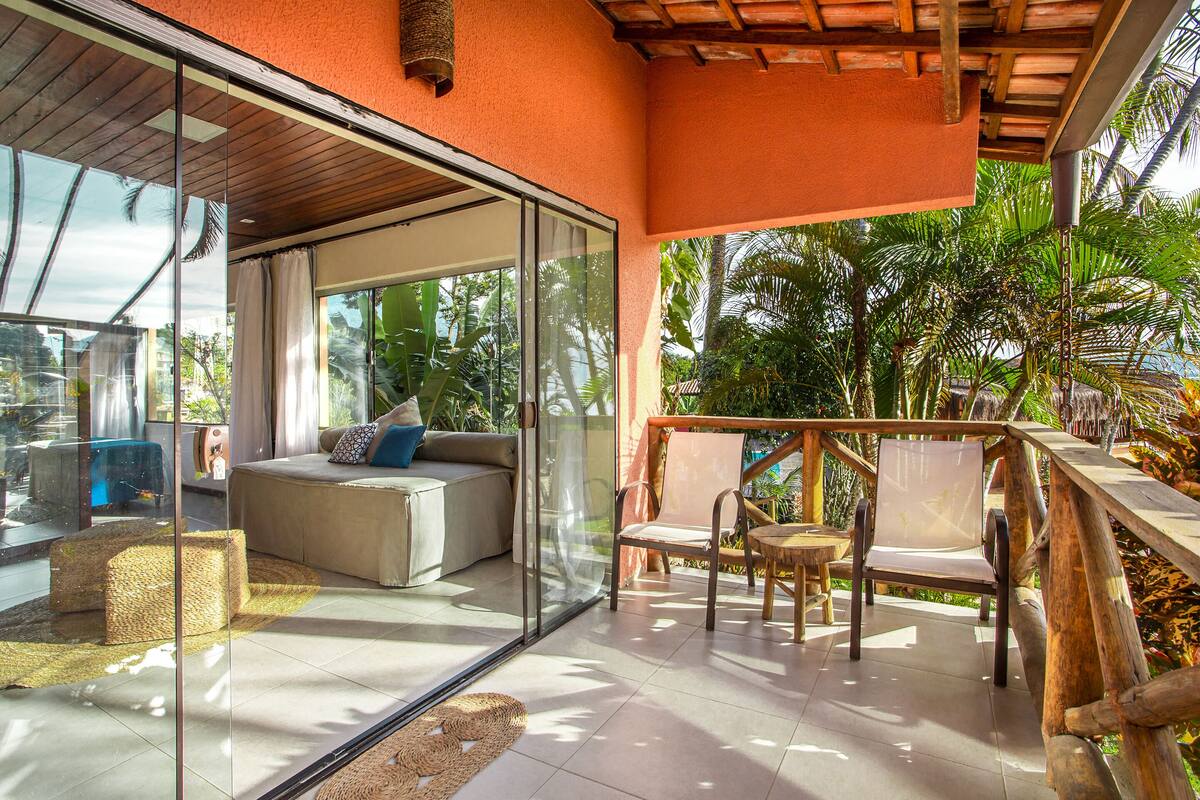 A modern living room with a glass wall, a sofa, and a wooden deck.