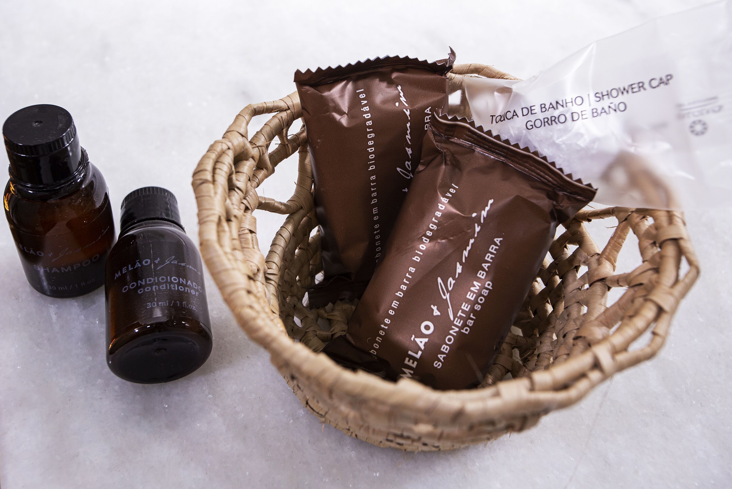 A wicker basket containing two brown bottles and a plastic bag with text, placed on a white surface.
