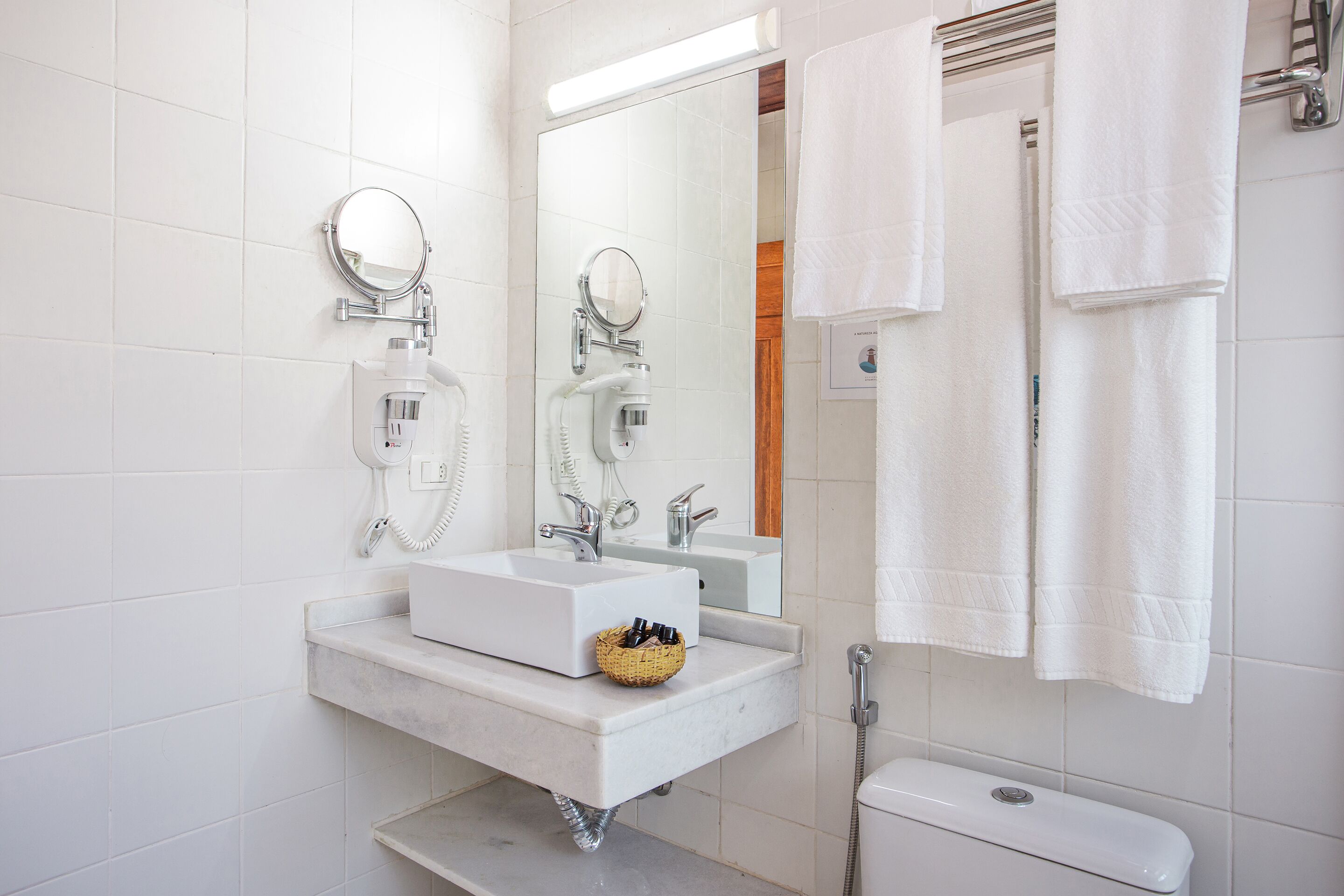 A modern bathroom with a white sink, mirror, and toilet.