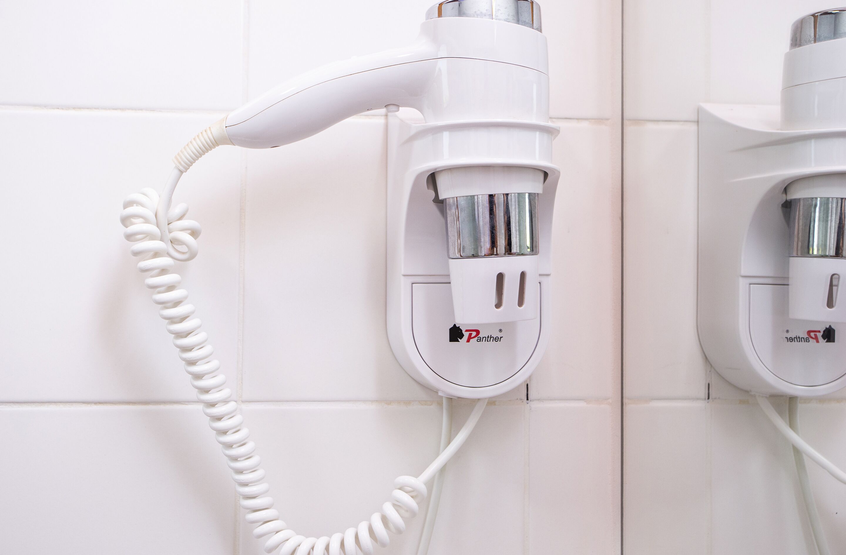 A wall-mounted hairdryer and a hair straightener connected to a power outlet.