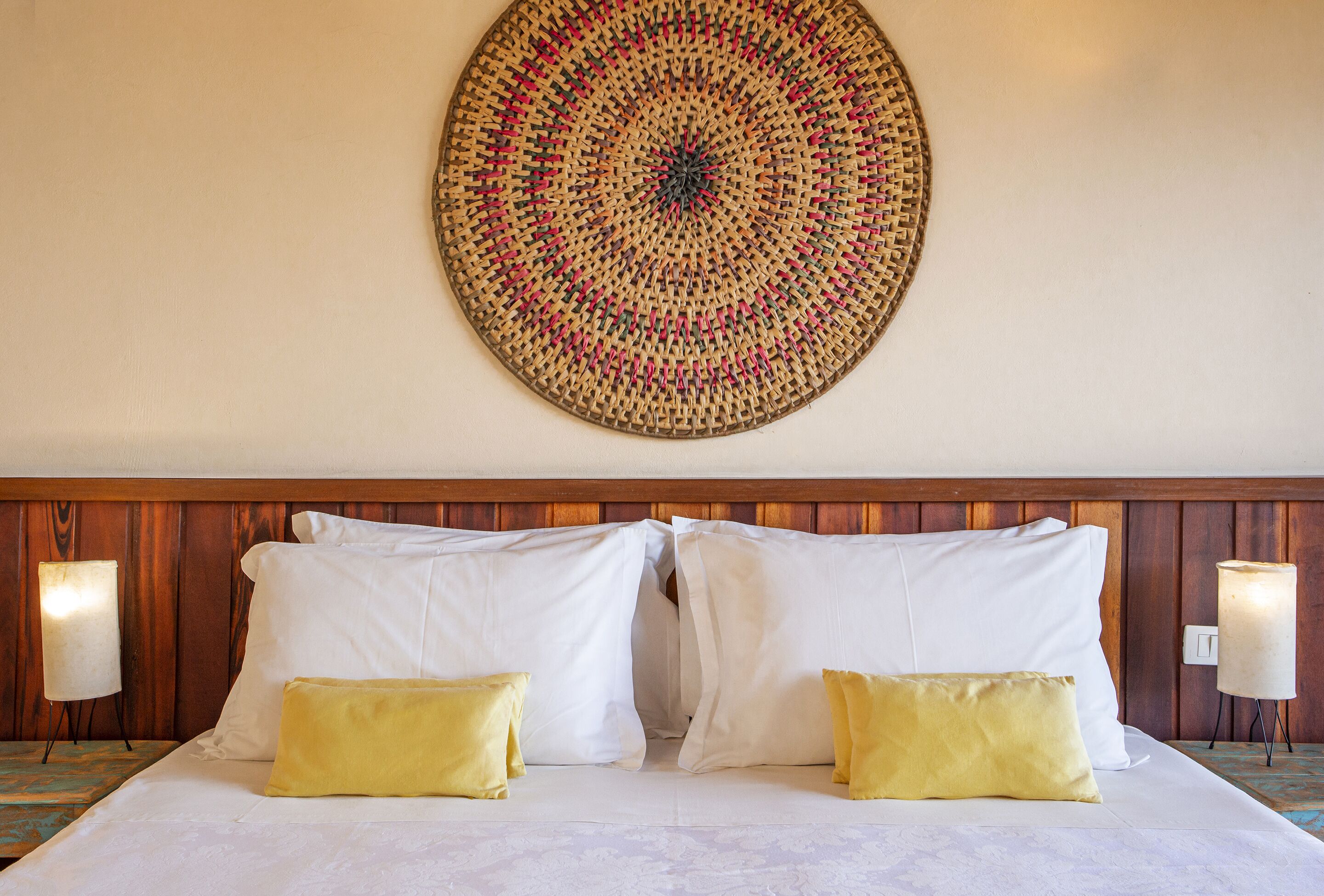 Una habitación de hotel con una cama grande, dos almohadas, un tapiz en la pared y dos lámparas de noche.