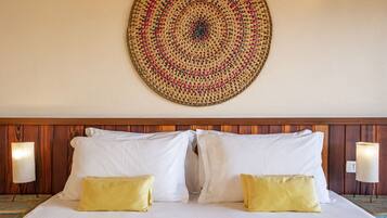 Una habitación de hotel con una cama grande, dos almohadas, un tapiz en la pared y dos lámparas de noche.