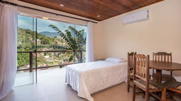 Quarto com uma janela grande, uma cama, uma mesa de madeira e uma cadeira.