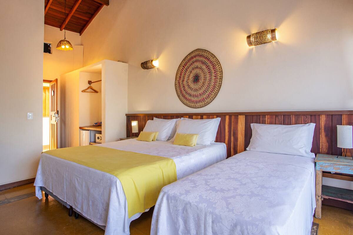 A room with two beds, a wooden headboard, a wall-mounted circular rug, and a hanging light fixture.
