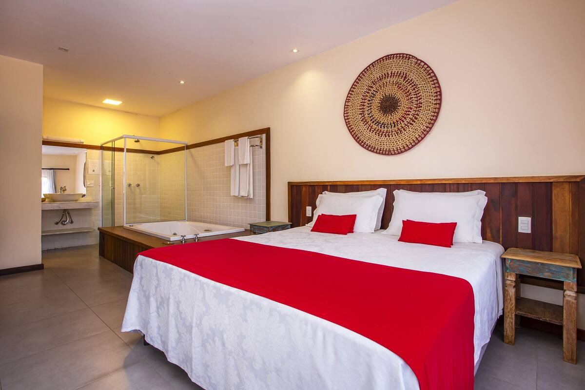 A hotel room with a large bed, a shower, and a bathroom with a sink and mirror.