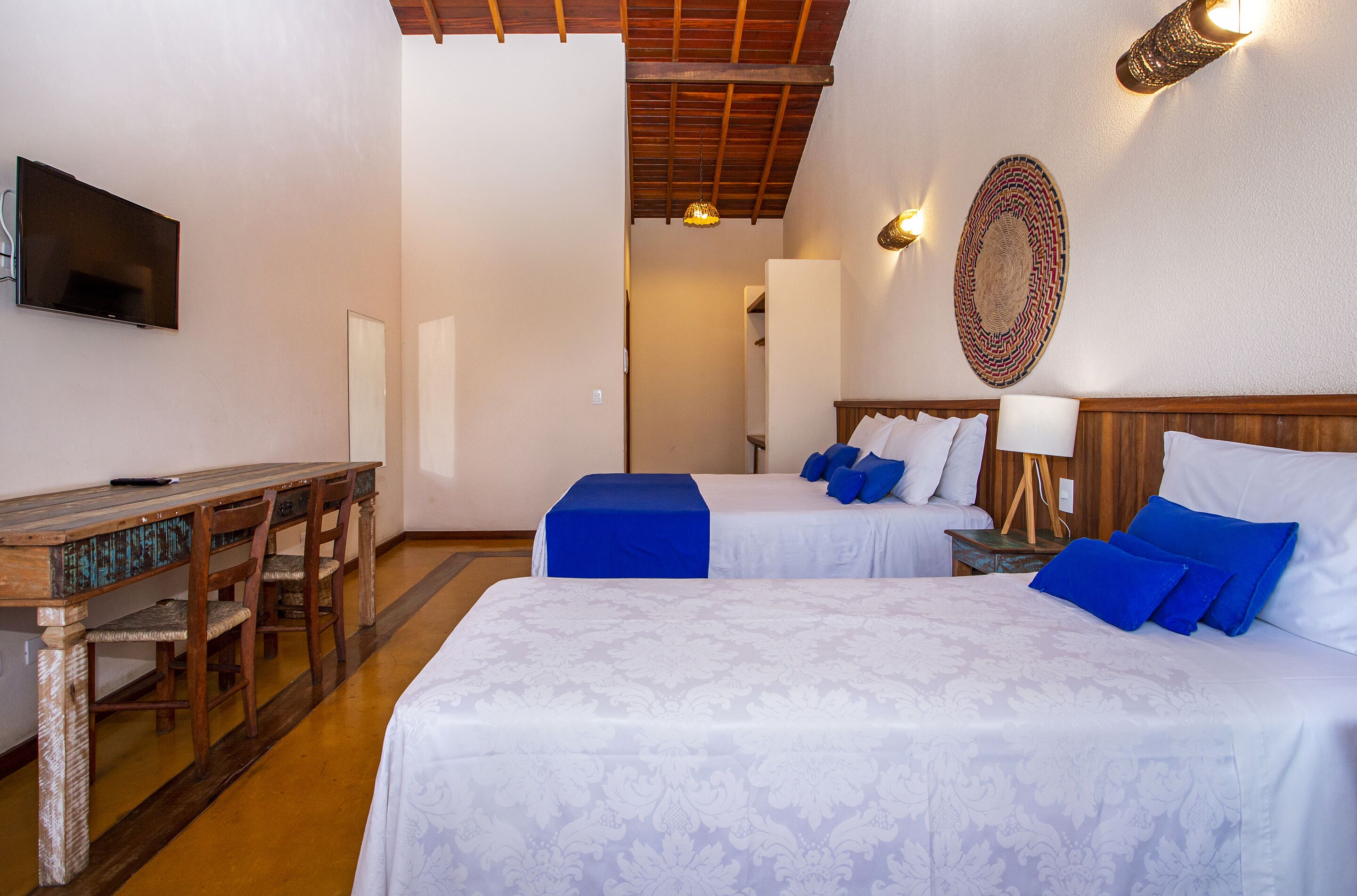 Une chambre d’hôtel avec deux lits, un bureau et une télévision.