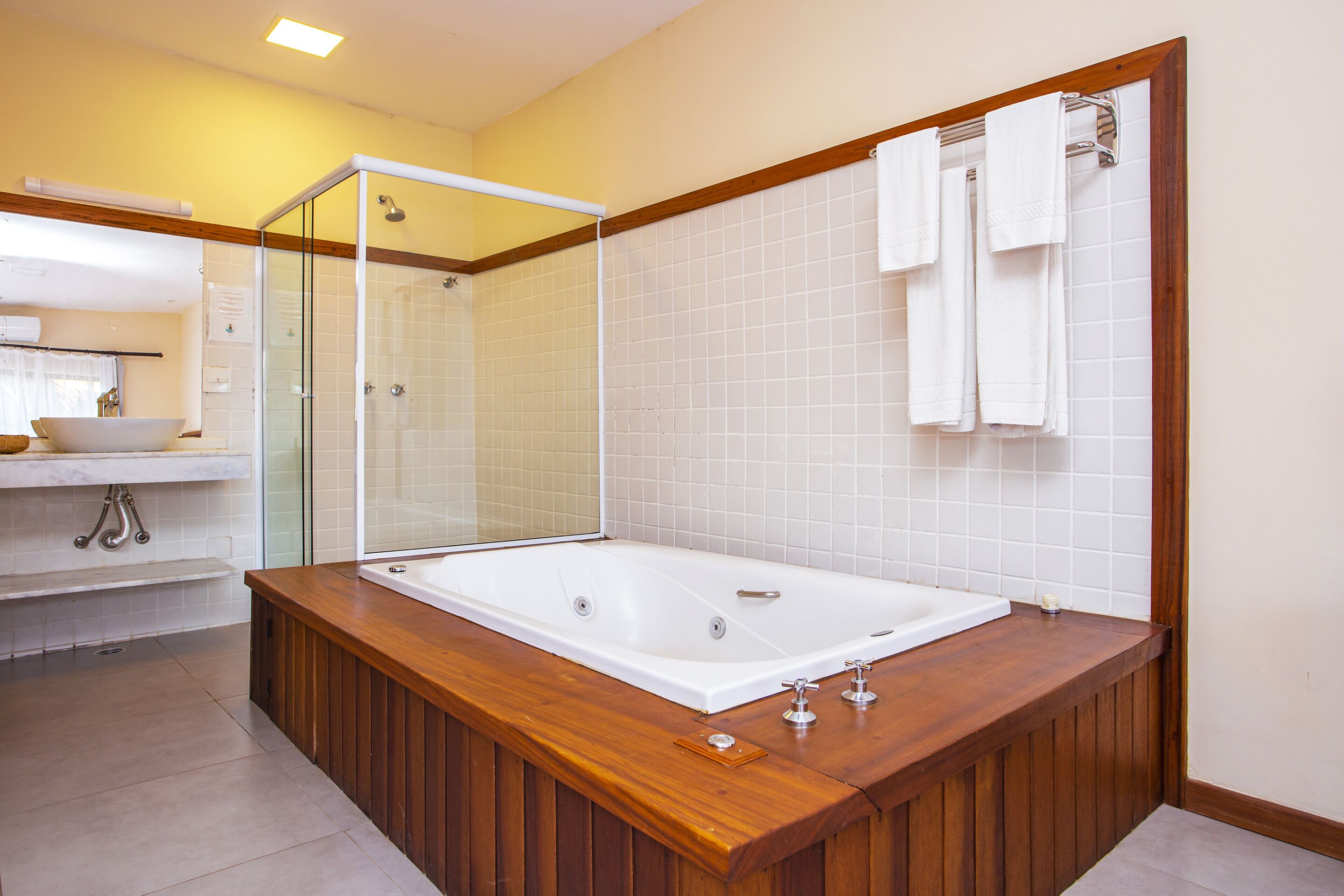 Un baño moderno con una bañera grande, una ducha con cerramiento de vidrio y un tocador de madera con lavabo.