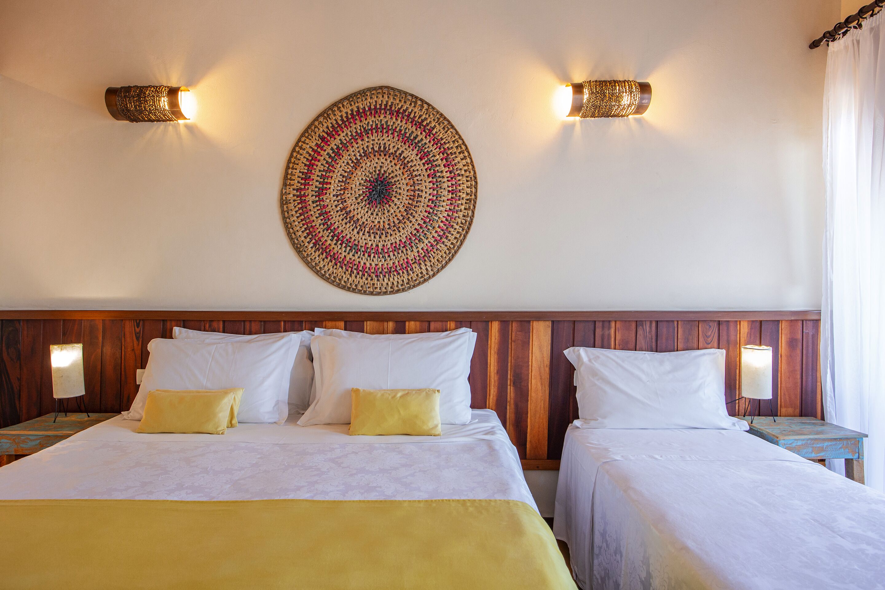 A hotel room with two beds, a wooden headboard, and a wall-mounted decorative piece.