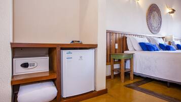 A hotel room with a bed, bedside table, and a small refrigerator.