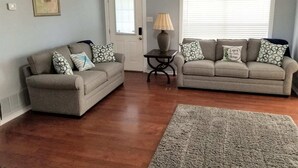 A living room with two grey sofas, a small table with a lamp, a grey rug, and a door with a window. - Pop's Lakefront Retreat.<br>Remodeled clean and comfortable. (Mabank)