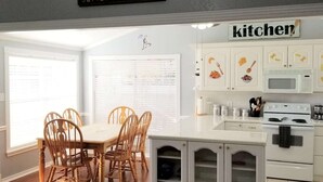 A kitchen with a dining area, featuring a sign that says "EVERYTHING IS BETTER AT THE LAKE" and a "kitchen" sign above the cabinets. - Pop's Lakefront Retreat.<br>Remodeled clean and comfortable. (Mabank)
