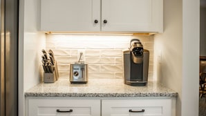 A kitchen with white cabinets, a coffee maker, and a knife block.