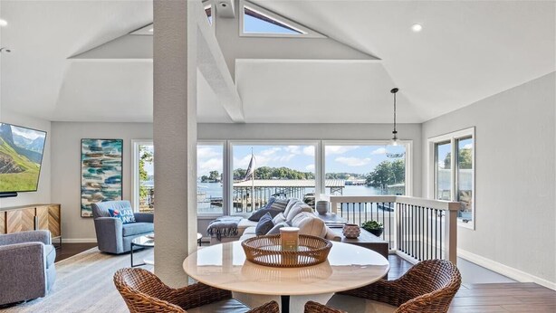 A spacious living area with a high ceiling, large windows, and a view of the outdoors. - New! Luxurious FLAT lot with private beach, dock, guest suite/apartment. (Lake Ozark)