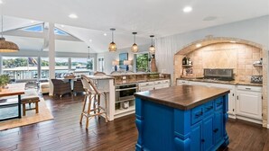 A spacious kitchen with a large island, white cabinetry, and a stone backsplash. - New! Luxurious FLAT lot with private beach, dock, guest suite/apartment. (Lake Ozark)