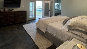 Une chambre à coucher avec un grand lit, une commode, un téléviseur et un plafond orné d’un motif original.