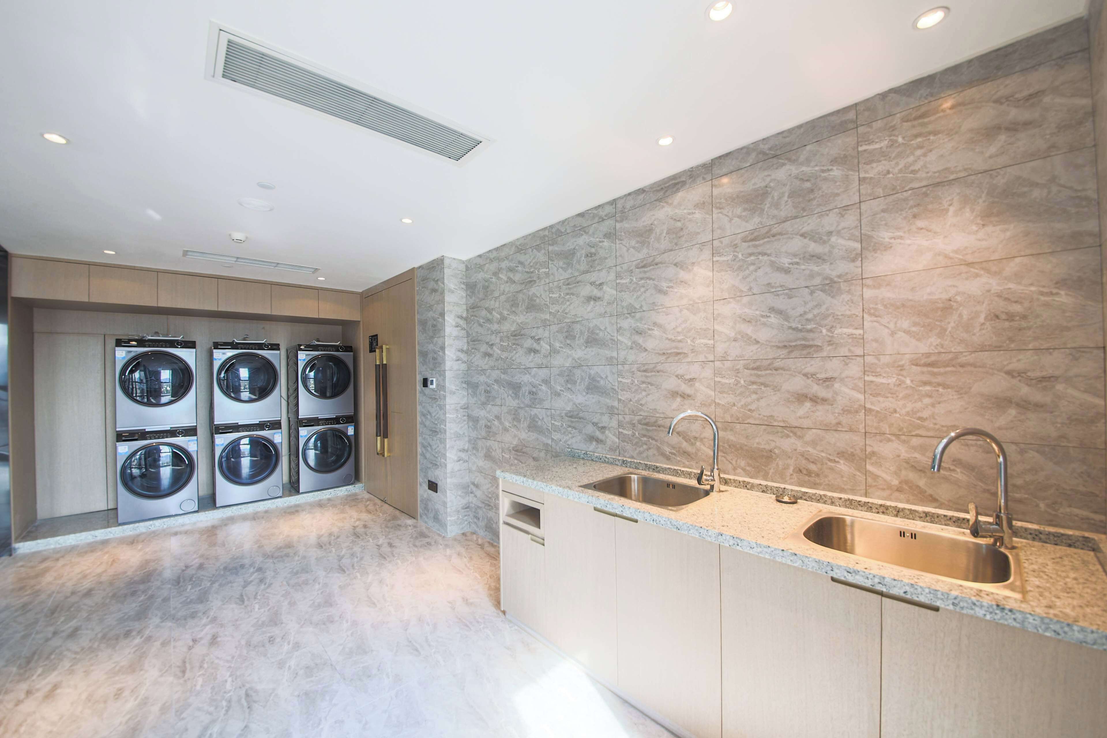 Een moderne keuken met een granieten aanrecht, een roestvrijstalen spoelbak en een ingebouwde wasmachine en droger.