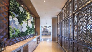 A modern hotel lobby with a marble reception desk, a green and white textured wall, and a patterned metal partition. - Howard Johnson By Wyndham Longxiang Hotel Ningbo (Ningbo)