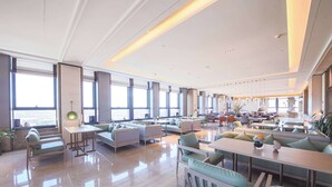 A spacious hotel lobby with seating areas, large windows, and a modern design. - Howard Johnson By Wyndham Longxiang Hotel Ningbo (Ningbo)