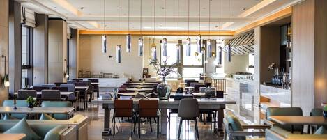 Un restaurante moderno con una barra larga, varias áreas de estar y lámparas colgantes.