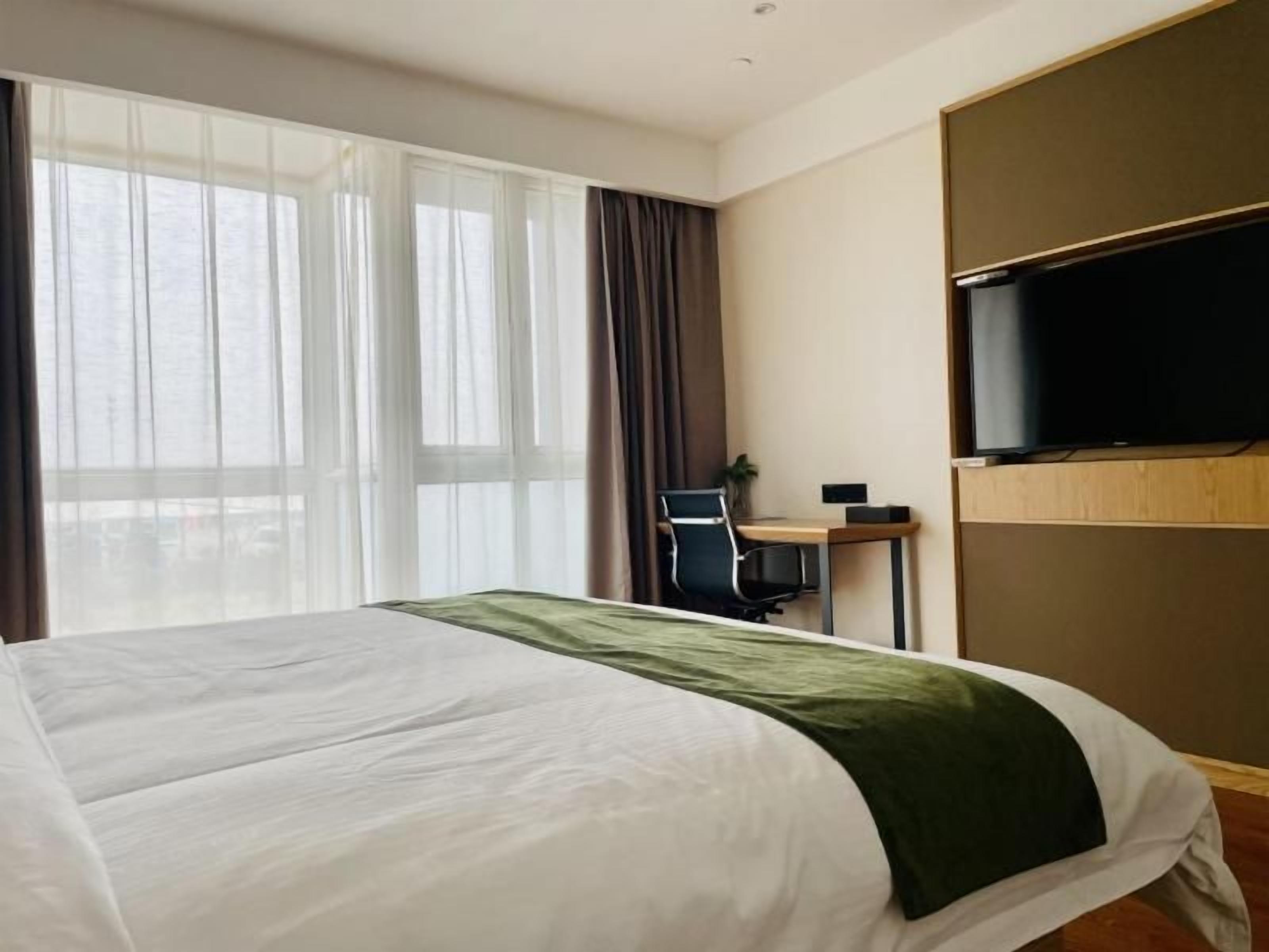 Une chambre d’hôtel équipée d’un lit, d’un bureau, d’une chaise et d’un téléviseur.
