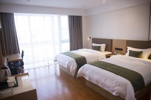 Habitación de hotel con dos camas, un escritorio y vistas al exterior.