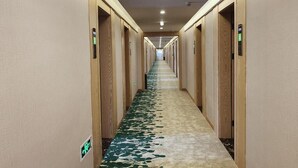 A hotel hallway with wooden doors, a carpet with a leaf pattern, and a long corridor. - Greentree Inn Express Jiangsu Suqian Shuyang County Bus Station (Suqian)