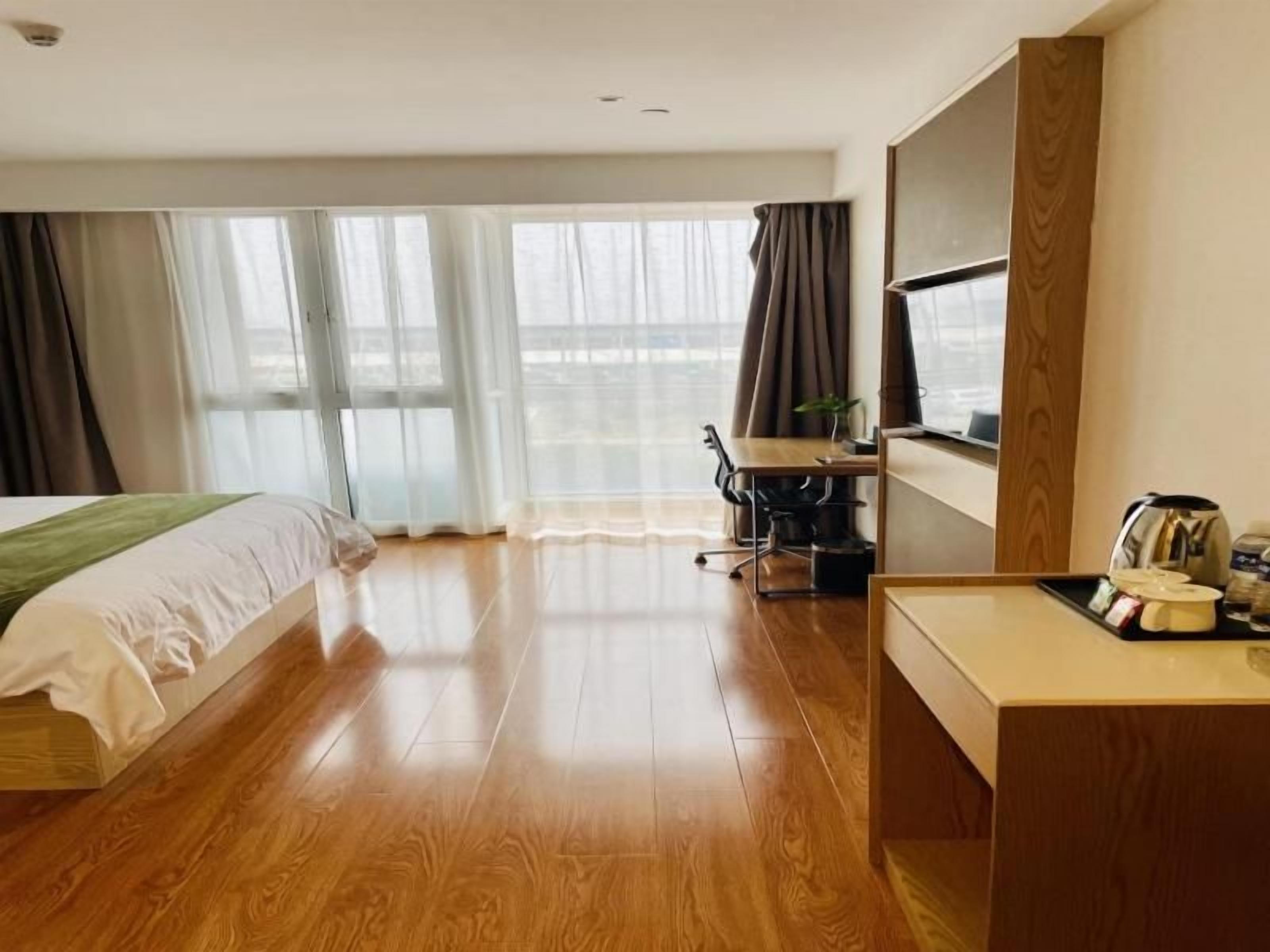 Ein Hotelzimmer mit Bett, Schreibtisch, Stuhl und großen Fenstern.