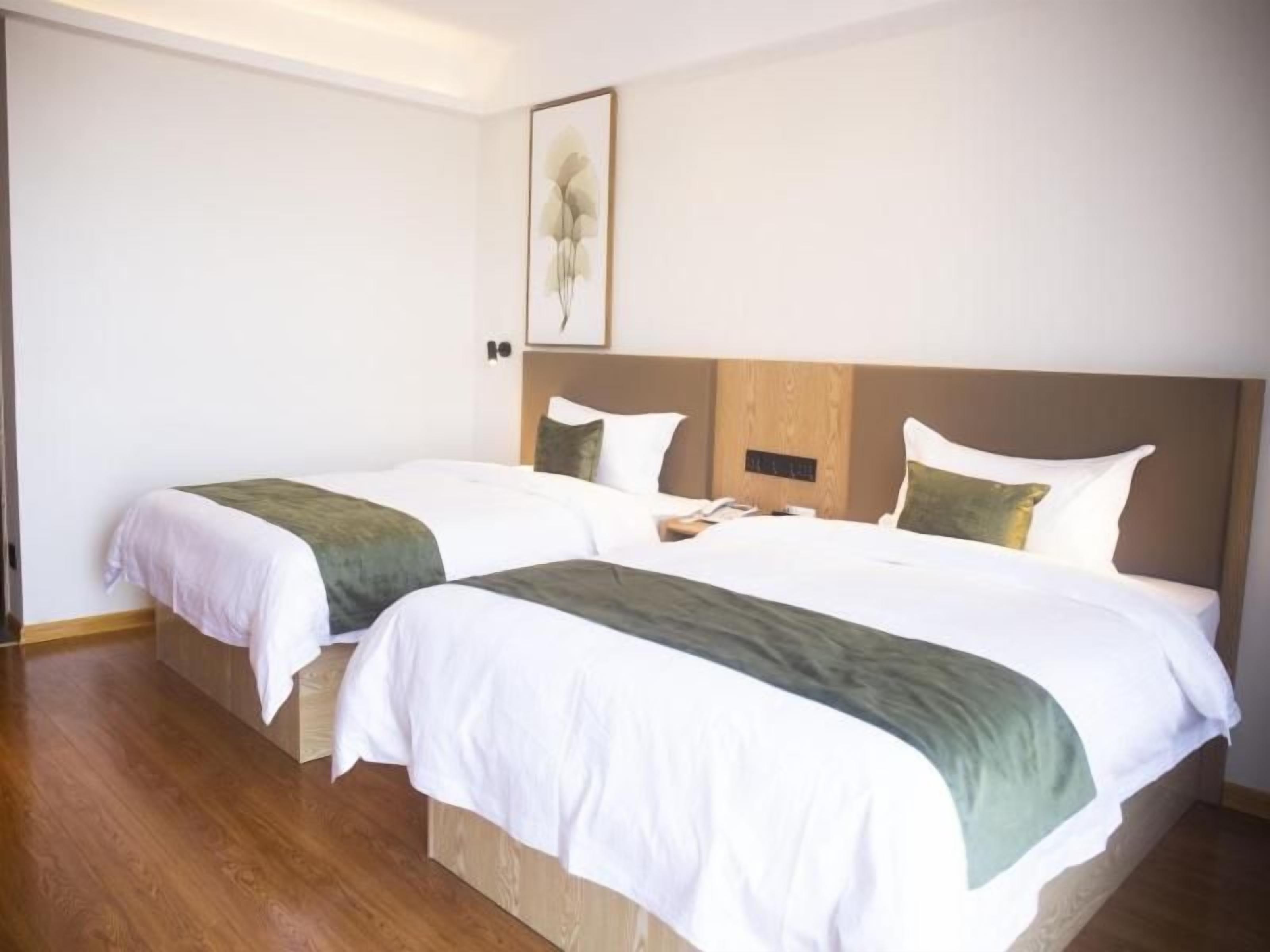 Habitación de hotel con dos camas, un cabecero de madera y una obra de arte enmarcada en la pared.
