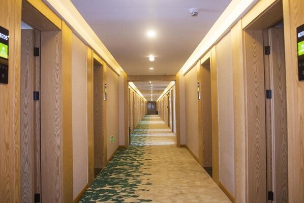 A hotel hallway with wooden paneling, a carpeted floor, and a series of doors on both sides. - Greentree Inn Express Jiangsu Suqian Shuyang County Bus Station (Suqian)