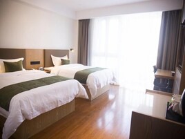 Una habitación de hotel con dos camas, un escritorio y un ventanal con cortinas.