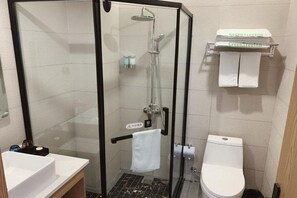 A bathroom with a glass-enclosed shower, a white toilet, and a sink. There is a towel rack with towels and a soap dispenser. - Greentree Inn Express Jiangsu Suqian Shuyang County Bus Station (Suqian)