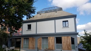 Un bâtiment moderne à deux étages, doté d’un toit plat, de grandes fenêtres et d’un espace mansardé apparent.